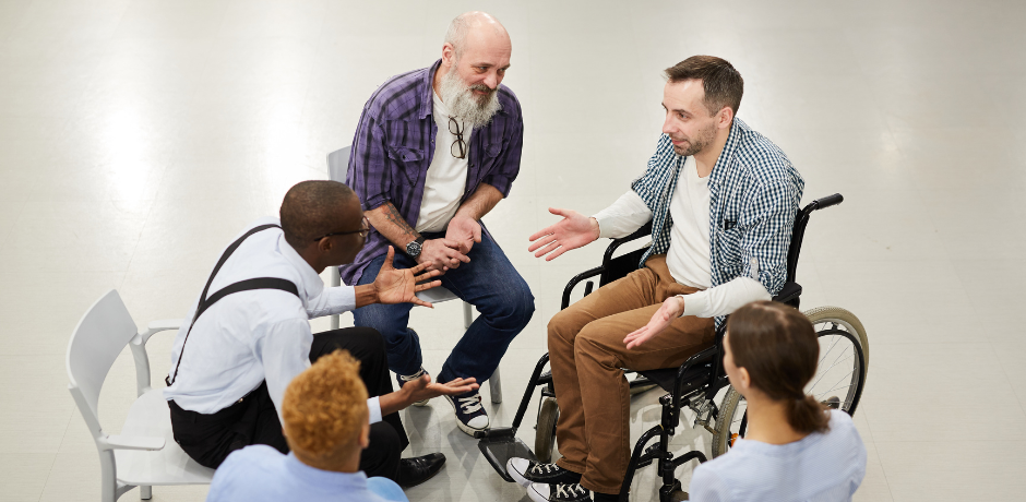 A group of adults discuss amongst themselves while sitting in a circle